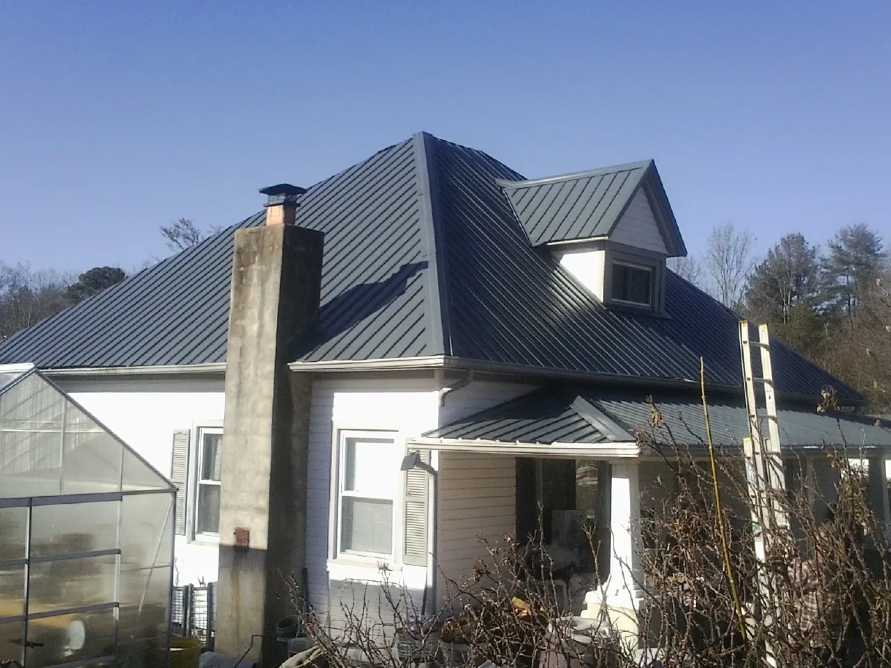 Dark blue standing seam metal roof on a white farmhouse with dormer — Slate & Tile Roof Repair by Roofing Brothers in South Orange