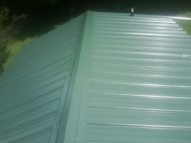New green metal panels meeting at the ridge of a roof — Flat Roof Repair work by our crew in South Orange