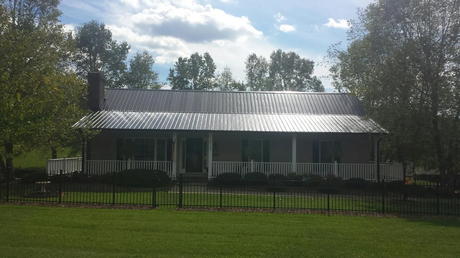 Gray metal roof on a brick ranch with a full width front porch — Gutter Guard Installation work by our crew in South Orange