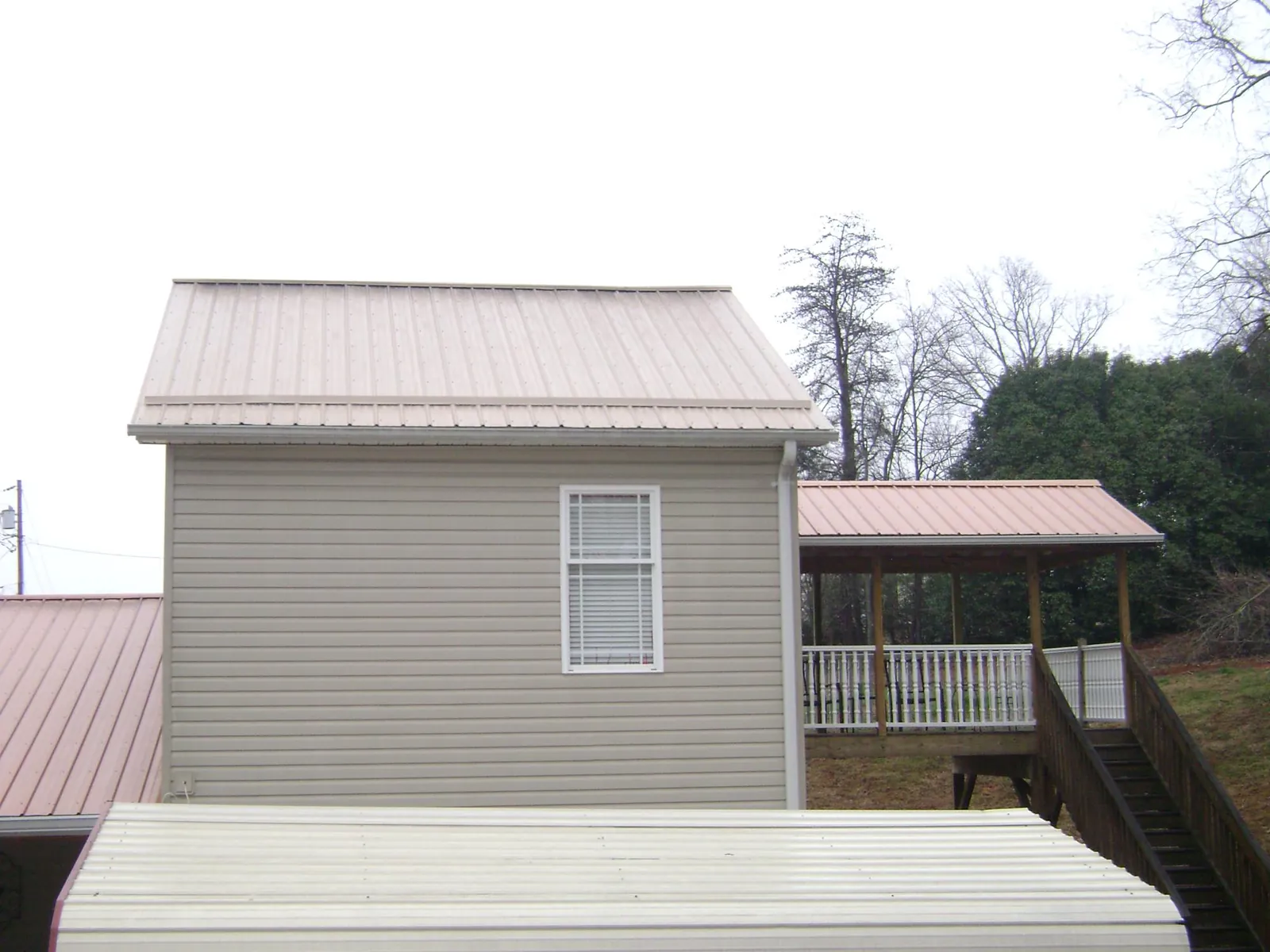 Tan metal roofs on a two story addition and attached porch, from a Roof Replacement job in South Orange